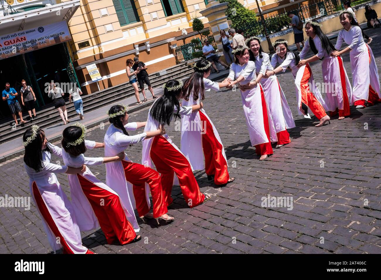 Groupe de filles à Ao Dai la robe traditionnelle jouant tug de guerre en dehors de la poste centrale, Ho Chi Minh Ville, Vietnam Banque D'Images