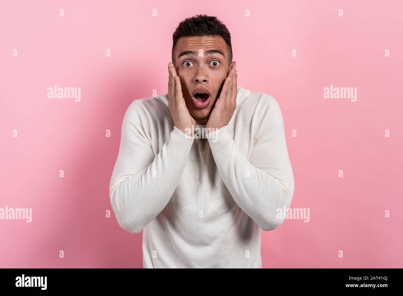 J'ai surpris le joli homme avec une bouche ouverte se posant dans le studio contre un fond rose regardant l'appareil photo.- image Banque D'Images