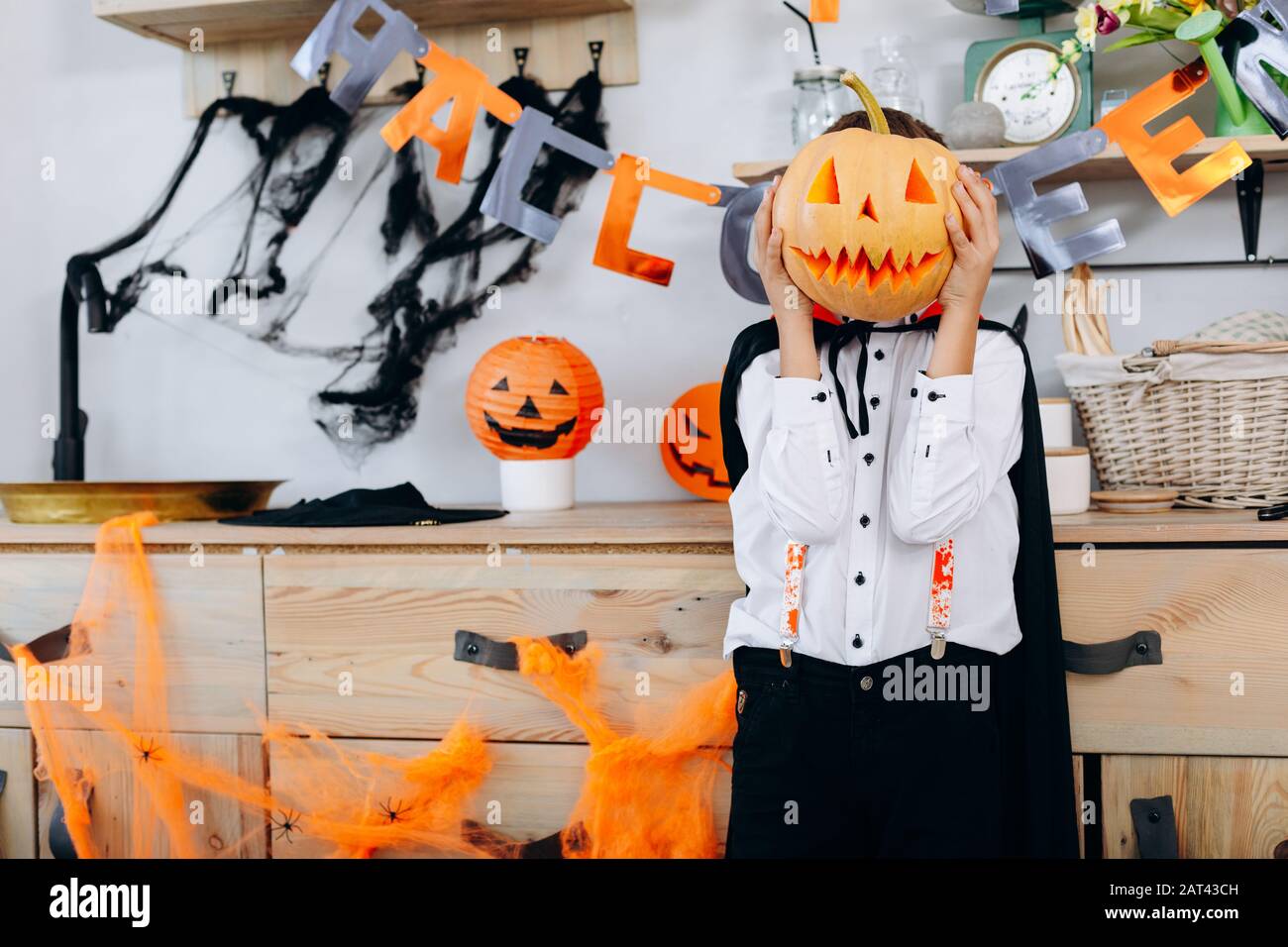Garçon debout dans une robe mascarade tenant une citrouille et cacher son visage- image Banque D'Images