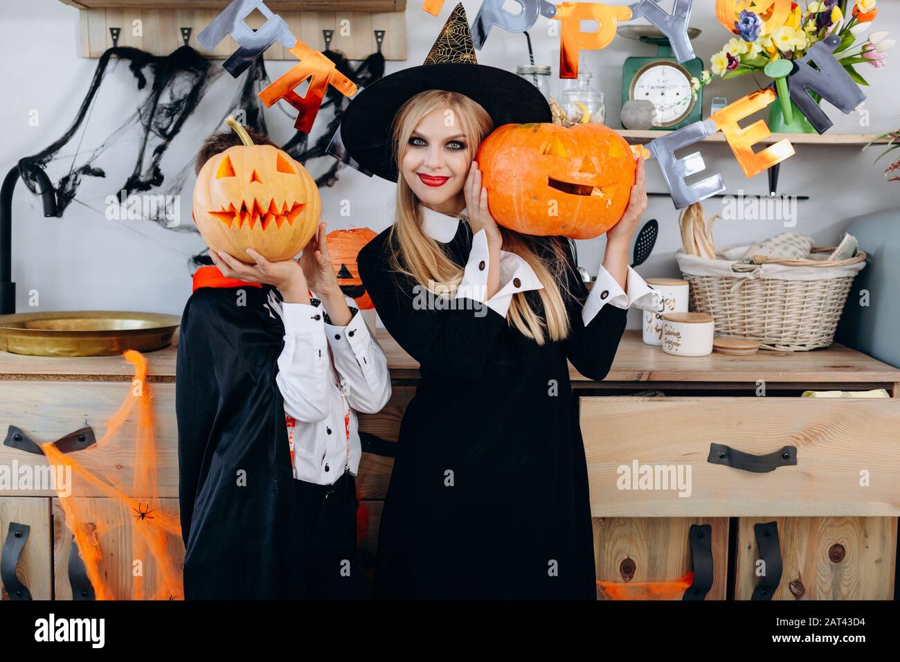 Mère et garçon debout dans une robe fantaisie tenant une citrouille. Garçon cacher son visage- image Banque D'Images