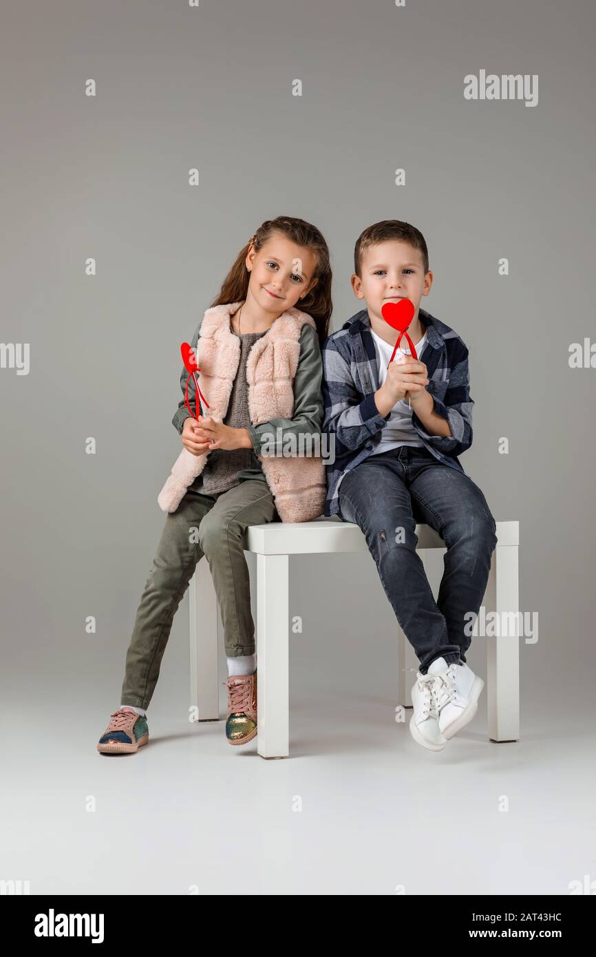 Joli petit couple fille et garçon avec coeurs rouges sur bâton dans des  vêtements tendance sitting ensemble au studio. Concept de mode pour  enfants. Saint-Valentin Photo Stock - Alamy