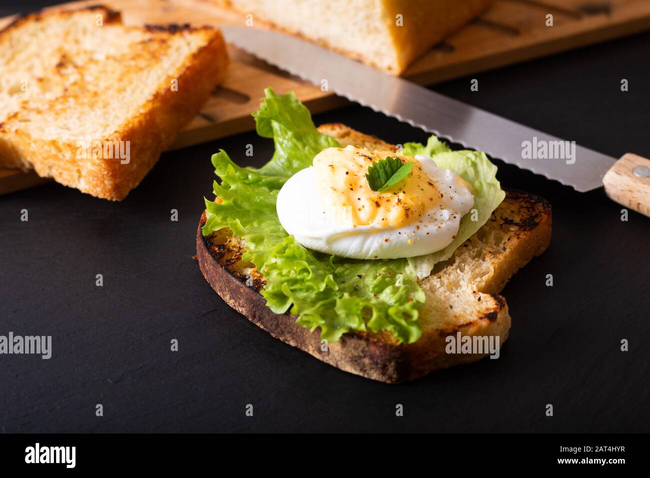 Concept de petit-déjeuner de nourriture bio composé d'œufs pochés maison ou d'œufs benoît sur pain au levain grillé sur tableau d'ardoise noire Banque D'Images