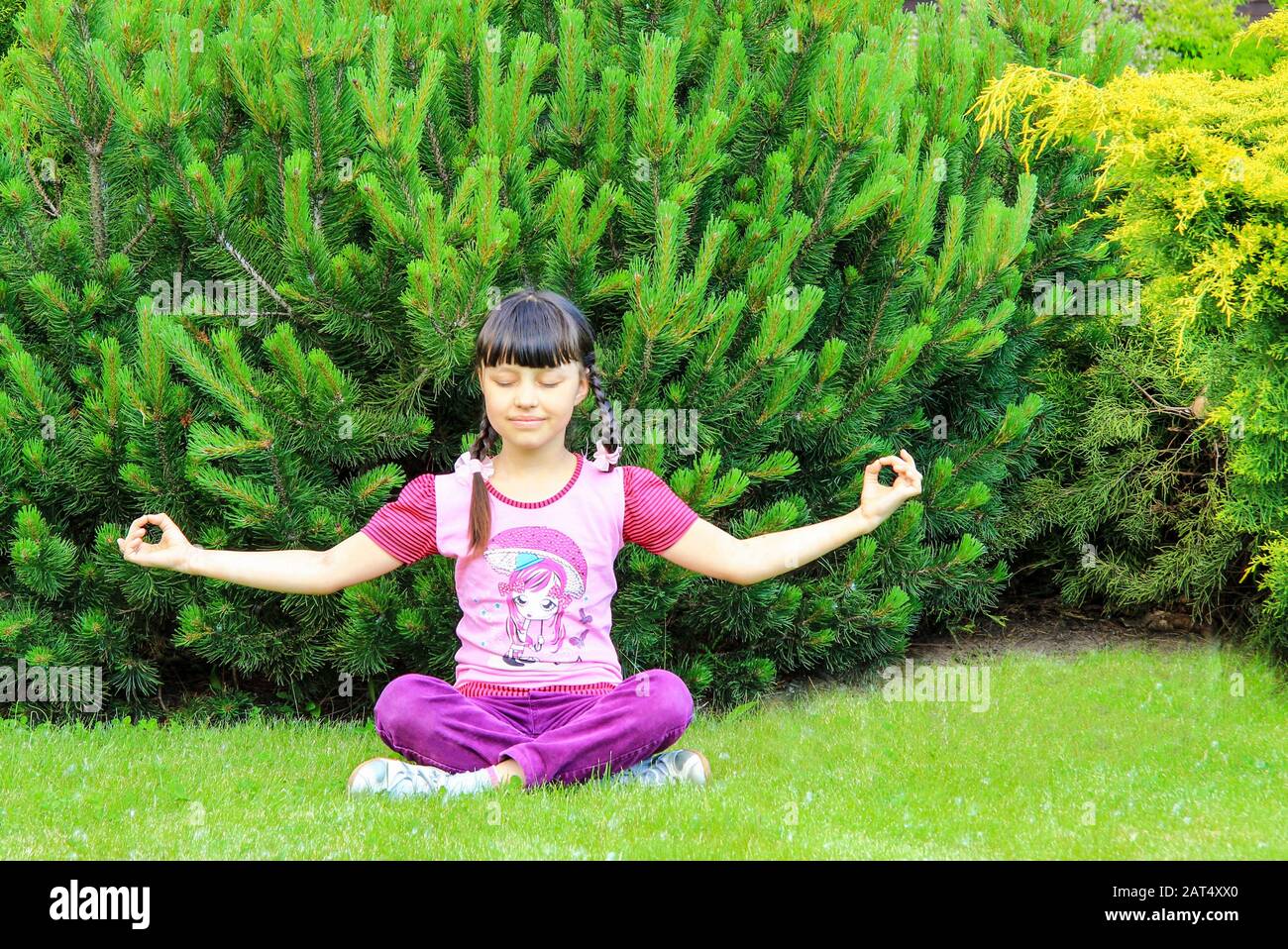 Une adolescente noire enlisée sourit et pratique le yoga dans le parc. Fille assise en position lotus, médite, sports d'été, Dnipro, Ukraine, 16.05.2018. Banque D'Images