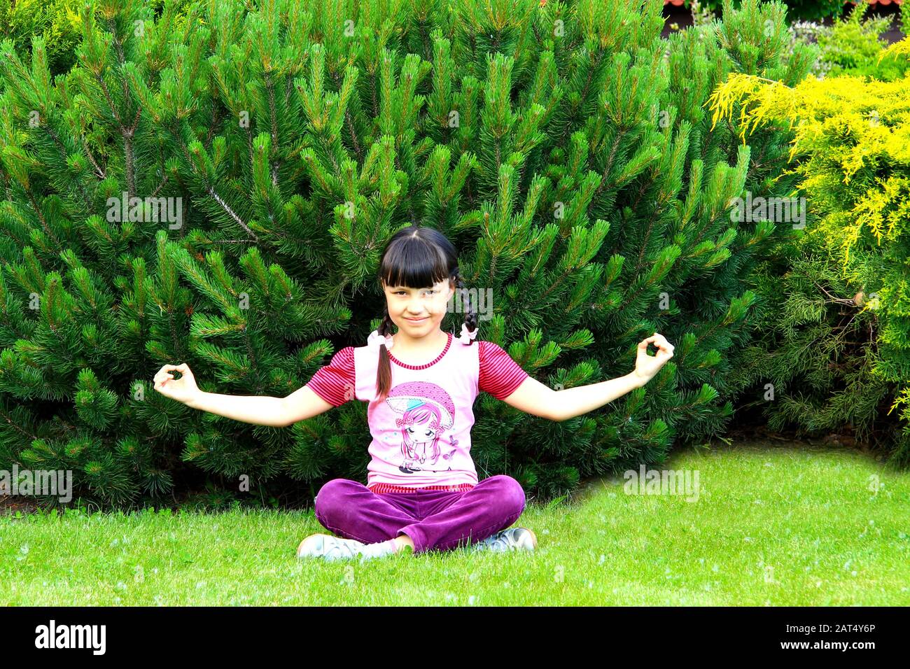 Une adolescente noire enlisée sourit et pratique le yoga dans le parc. Fille assise en position lotus, médite, sports d'été, Dnipro, Ukraine, 16.05.2018. Banque D'Images