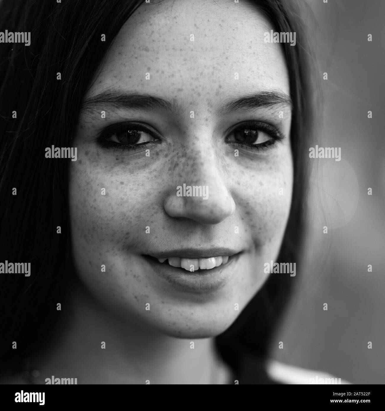 Headshot d'une jolie jeune fille d'université blanche de 18 ans avec de gros yeux bruns se posant contre un mur en bokeh Banque D'Images