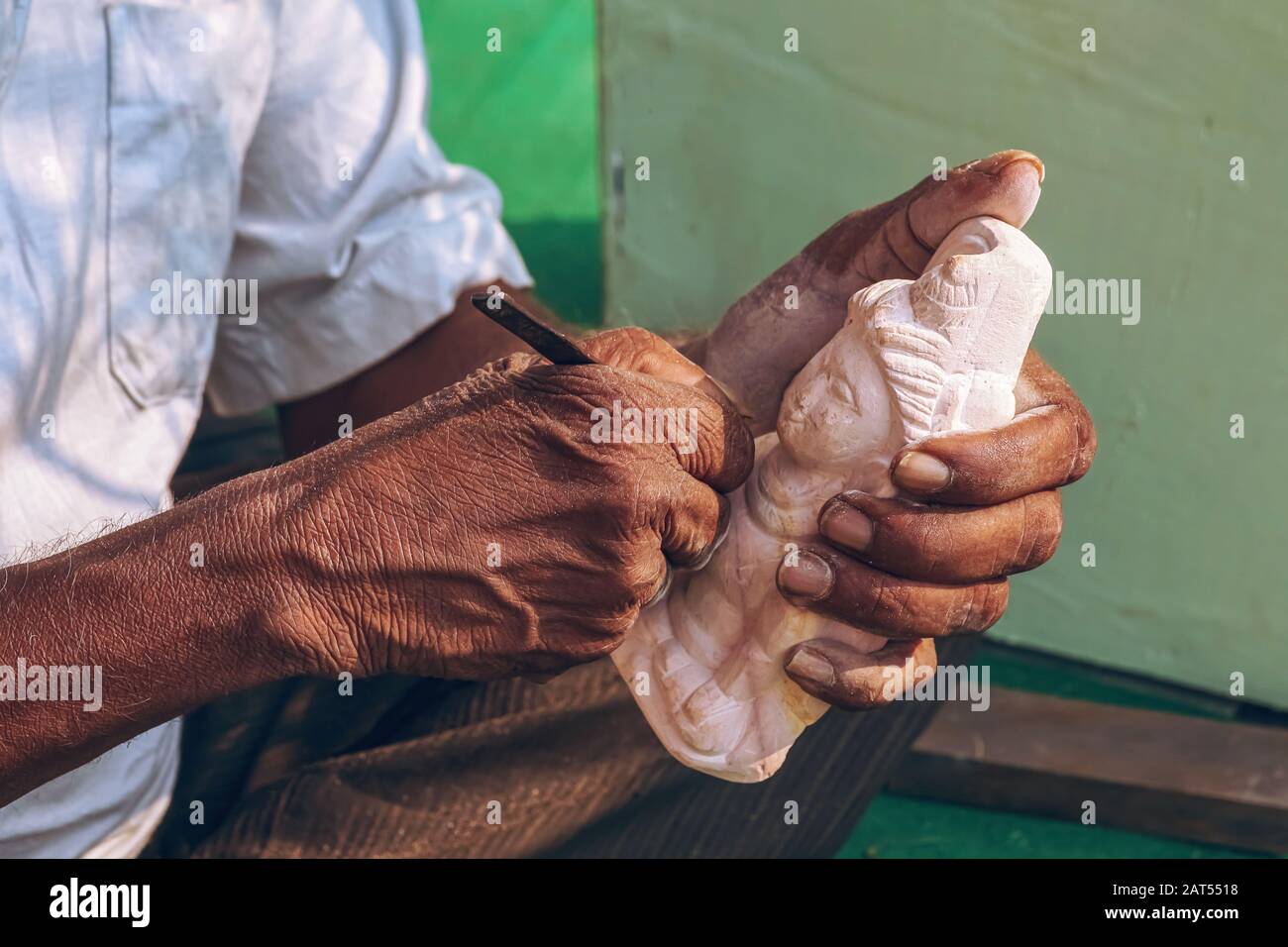 Artiste mains dans vue rapprochée travaillant avec un burin sur une sculpture miniature en pierre de Dieu indien Shiva Banque D'Images