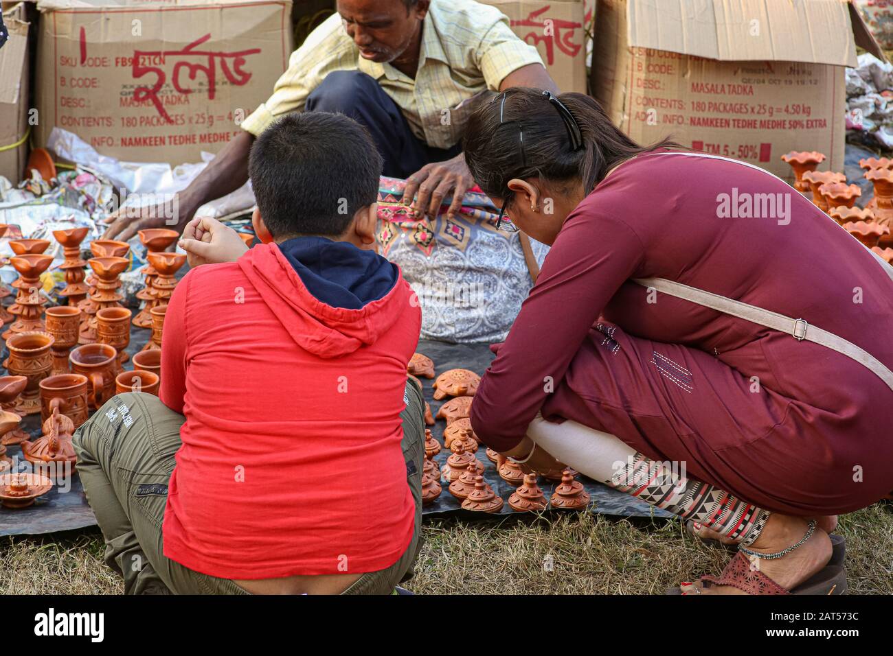 Femme client choisissant des articles d'artisanat à vendre avec son fils à son côté à un tarif d'artisanat à Kolkata Banque D'Images