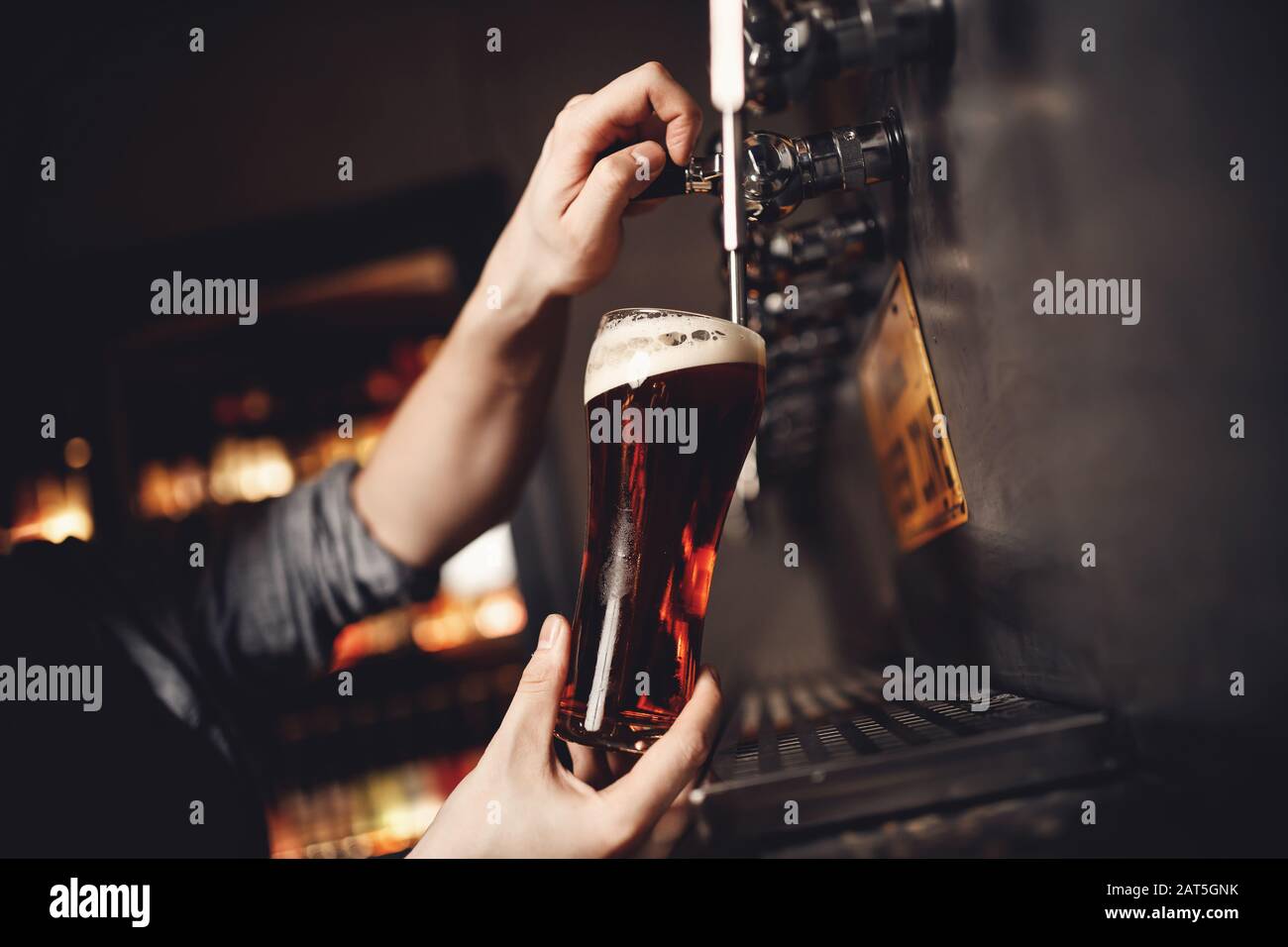 Les barman boivent de la bière artisanale à partir du robinet en verre, fond sombre Banque D'Images