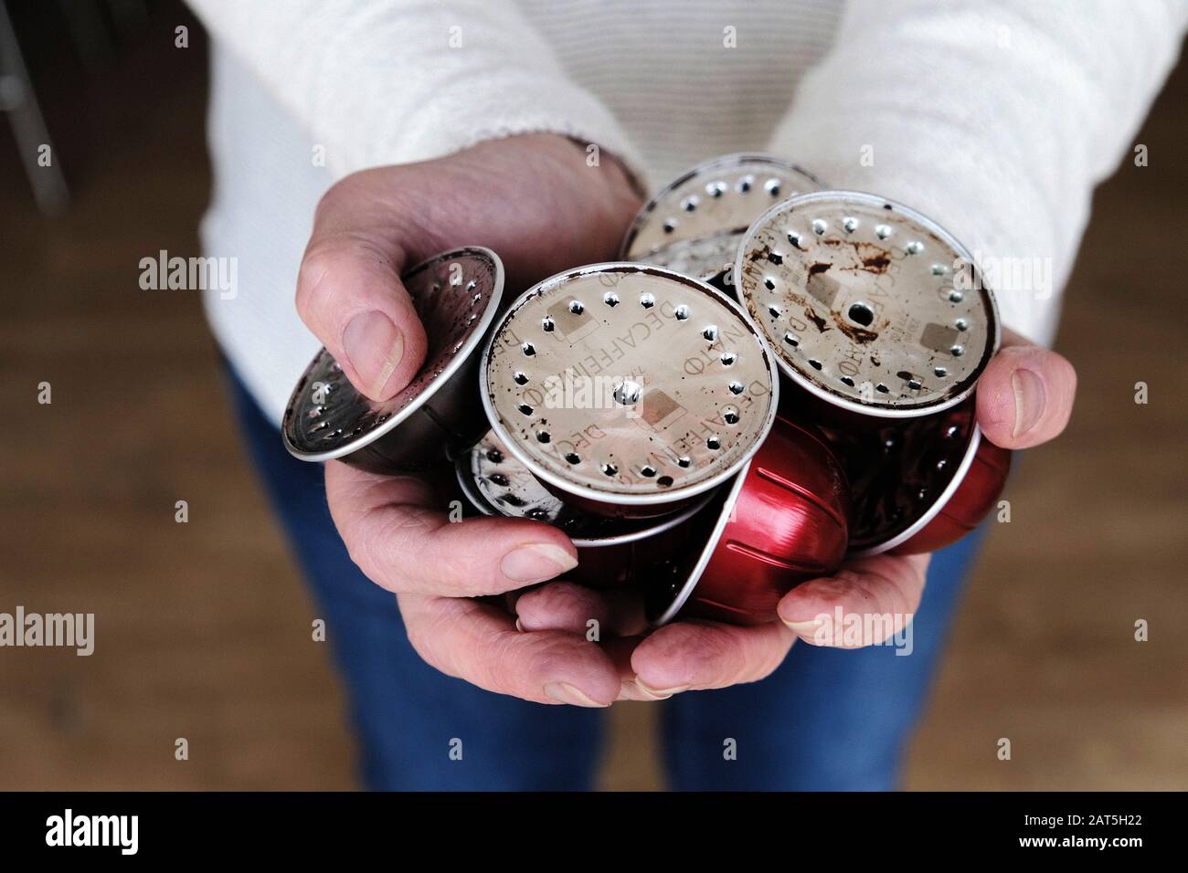 Une femme tenant une poignée de dosettes ou capsules en aluminium d'occasion d'une machine à café Nespresso. Les dosettes sont conservées pour être recyclées Banque D'Images