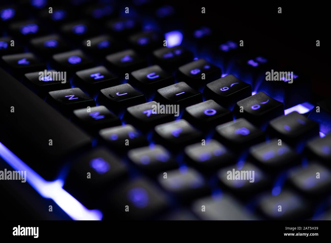 Lettres sur un clavier bleu lumineux bleu en gros plan sombre Banque D'Images