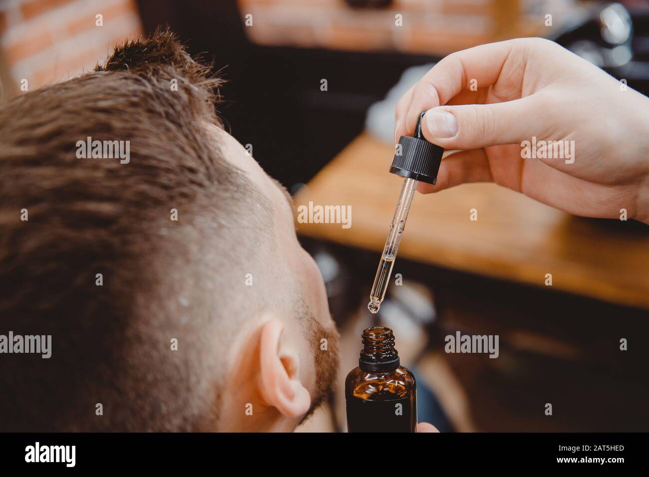 Barber applique de l'huile de barbe avec compte-gouttes pour homme dans la barbarbares Banque D'Images