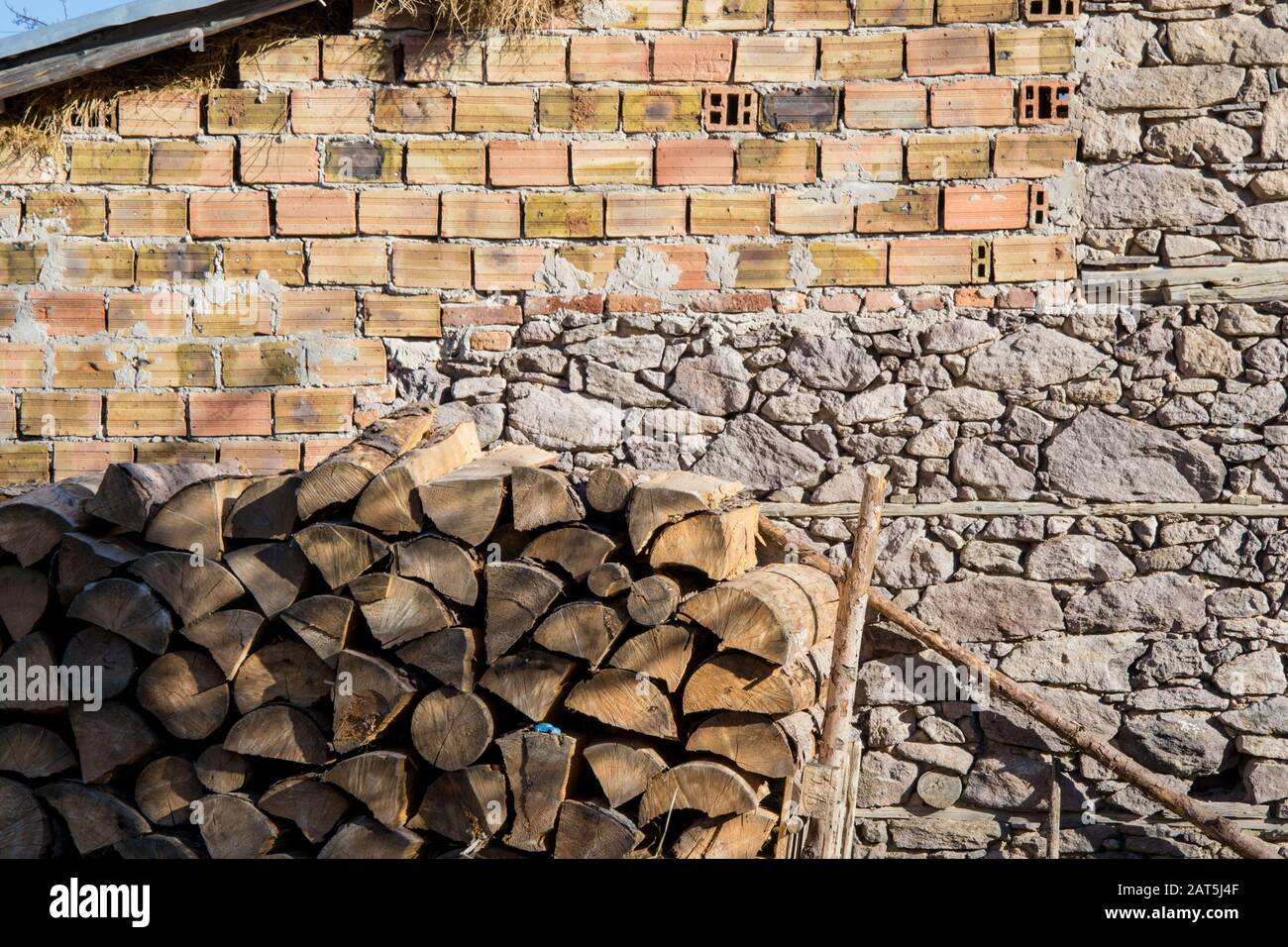 Pile de bois devant mur inachevé avec briques. Grumes, combustible pour chauffage. Bois de chauffage empilé Banque D'Images