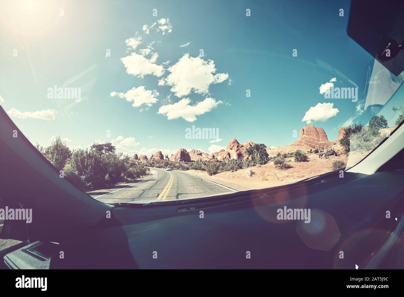 Conduite contre le soleil, image dans un ton vintage d'une route prise à partir du siège avant d'une voiture, lentille torchère présente, États-Unis. Banque D'Images