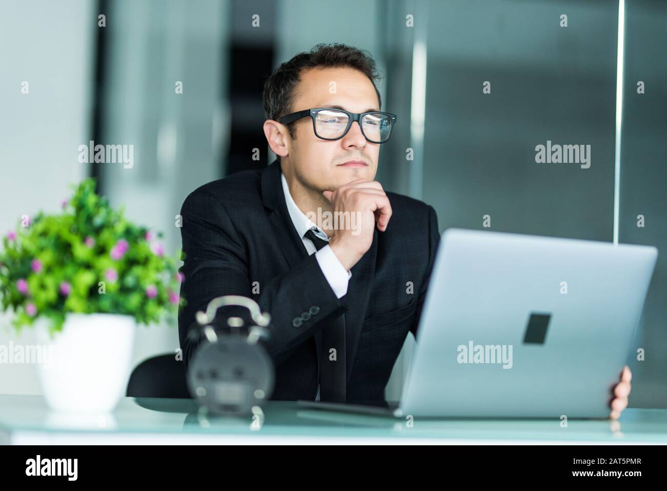 Jeune manager sitting at desk in bright office, travailler sur ordinateur portable. Banque D'Images