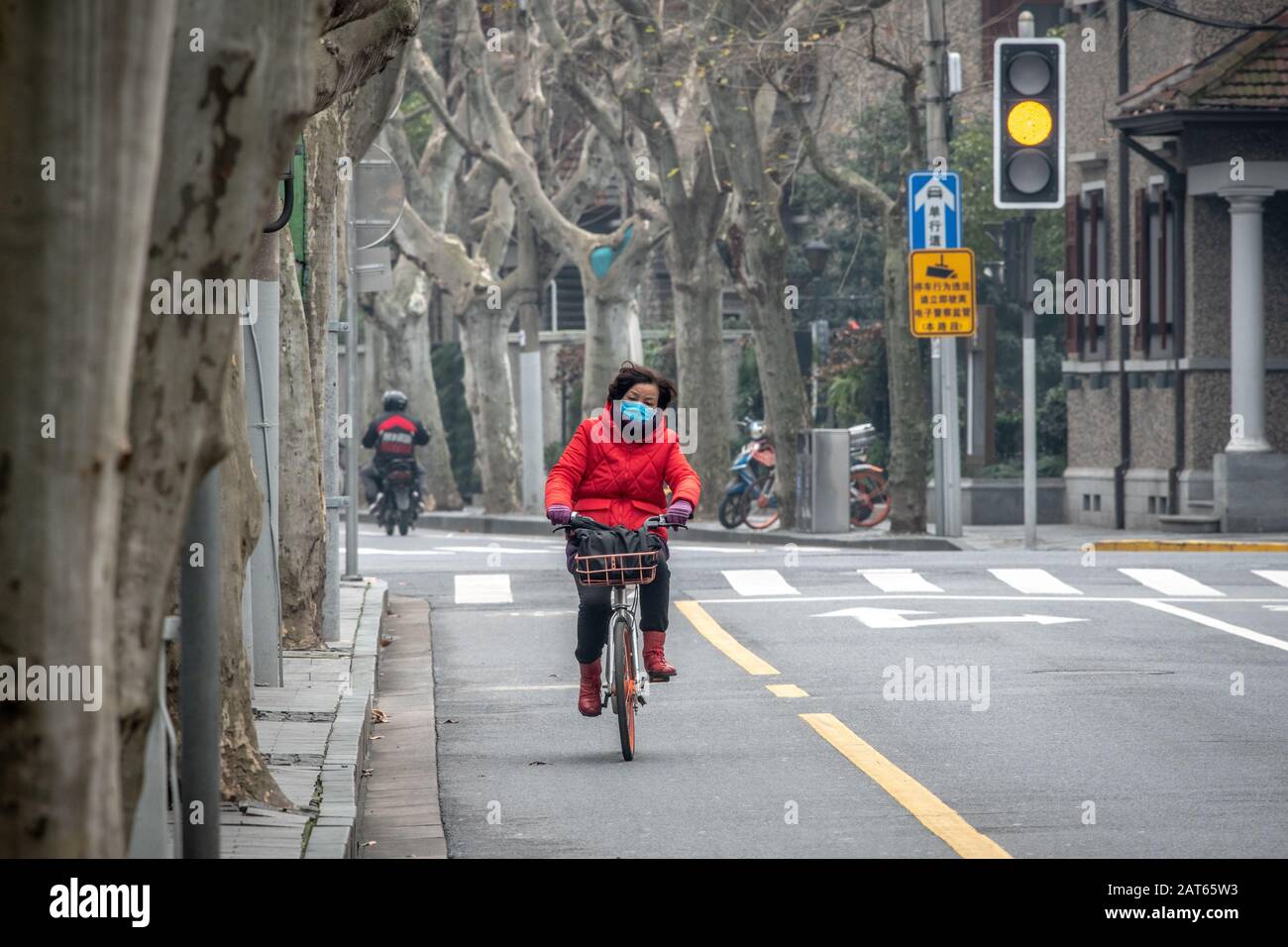 Shanghai, Chine, 27 janvier 2020, une femme qui monte son vélo portant un masque sur une route presque vide pour éviter de prendre le Coronavirus Banque D'Images