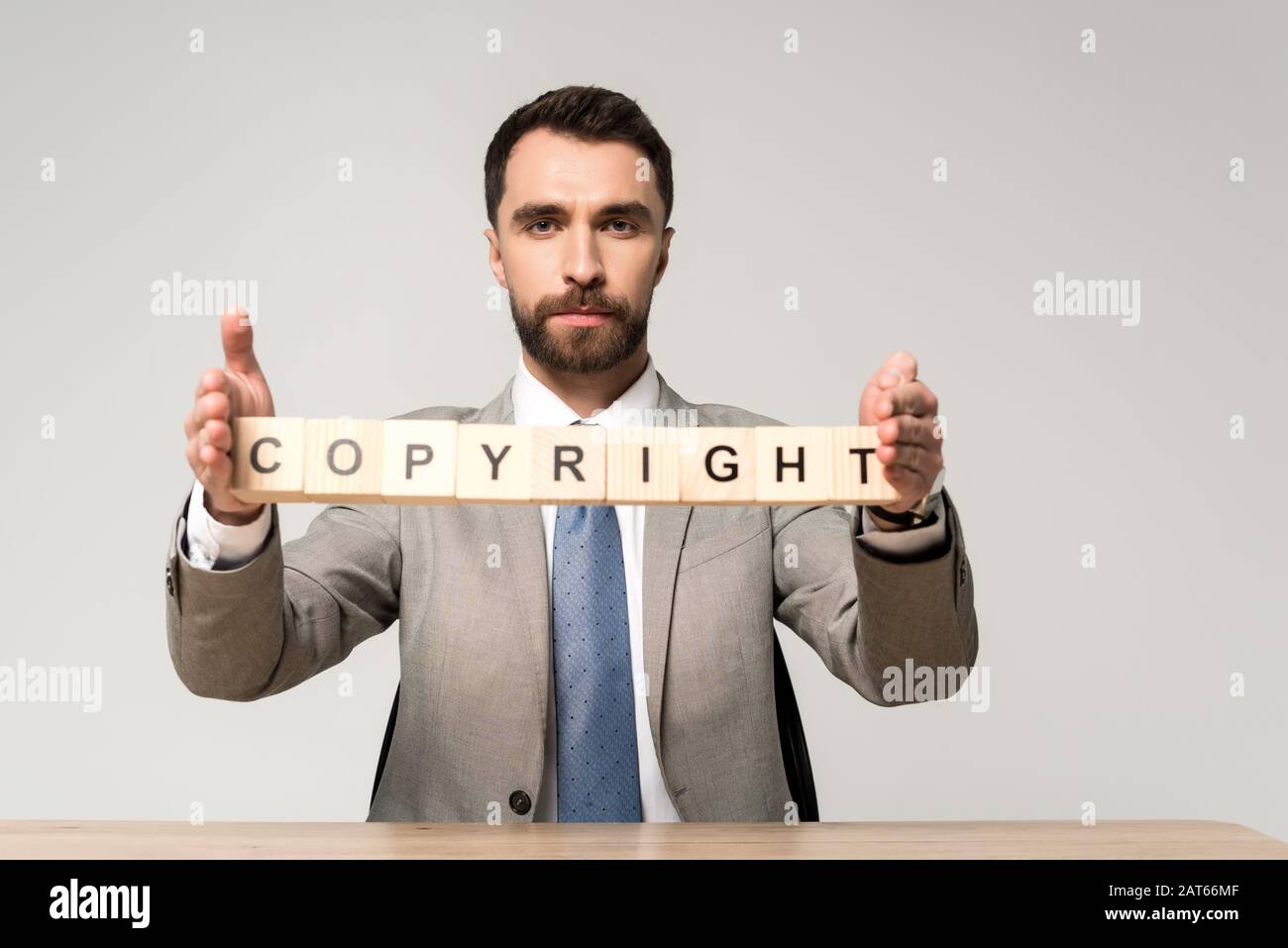 homme d'affaires confiant tenant des cubes de bois avec des lettres de copyright isolées sur gris Banque D'Images