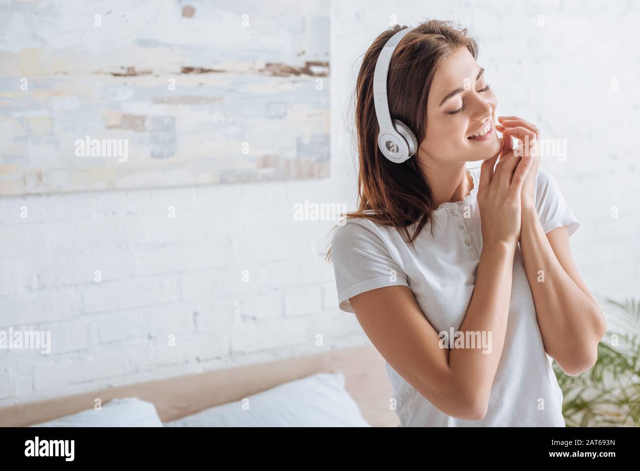 une femme gaie aux yeux fermés souriant et écoutant de la musique à la maison Banque D'Images