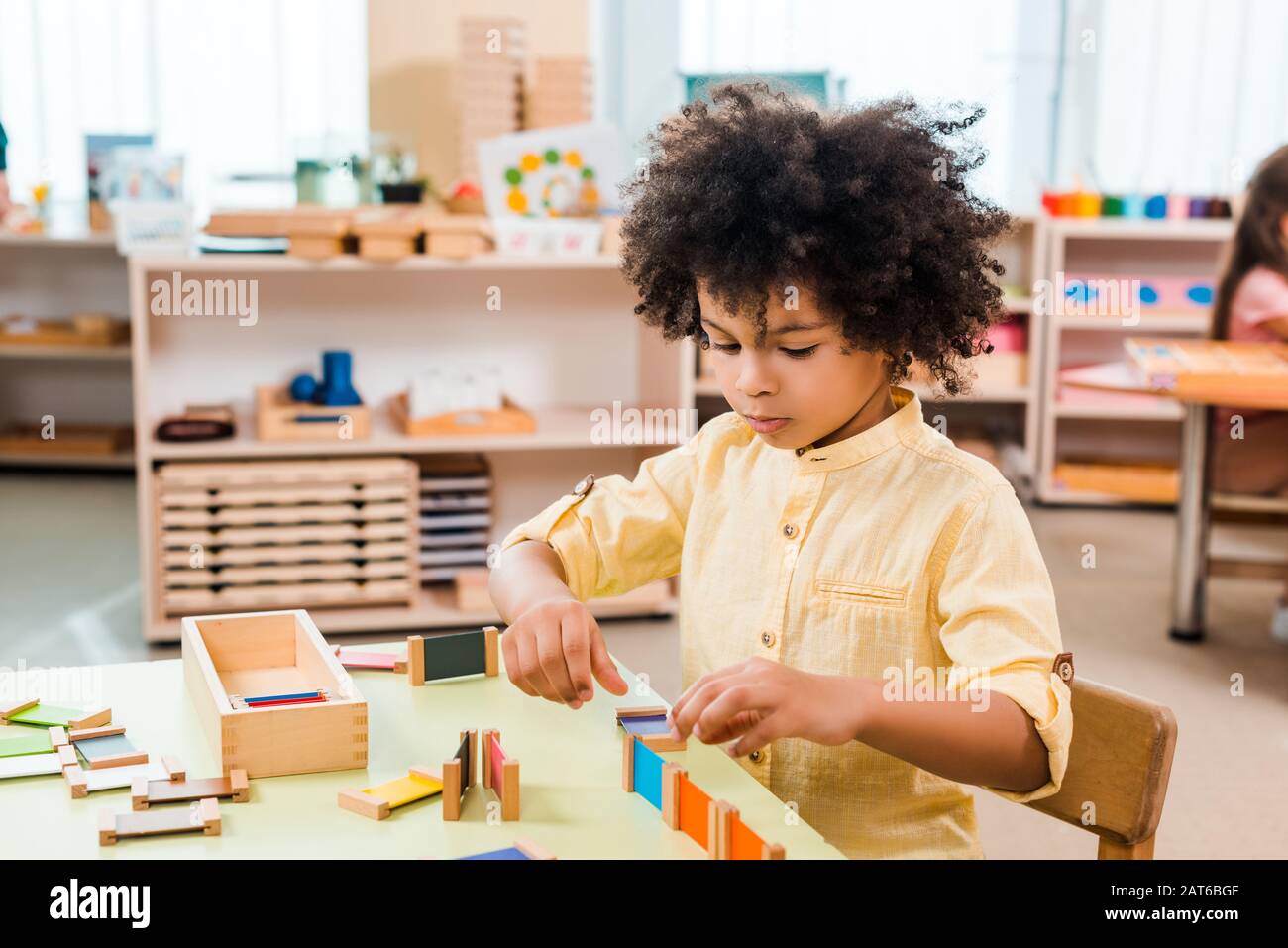 Foyer sélectif des enfants africains américains jouant au jeu éducatif à la table à l'école de montessori Banque D'Images