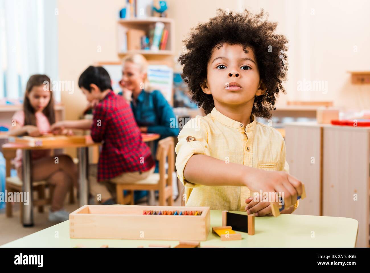Foyer sélectif de l'enfant africain américain avec jeu en bois et professeur avec des enfants à l'école de montessori Banque D'Images