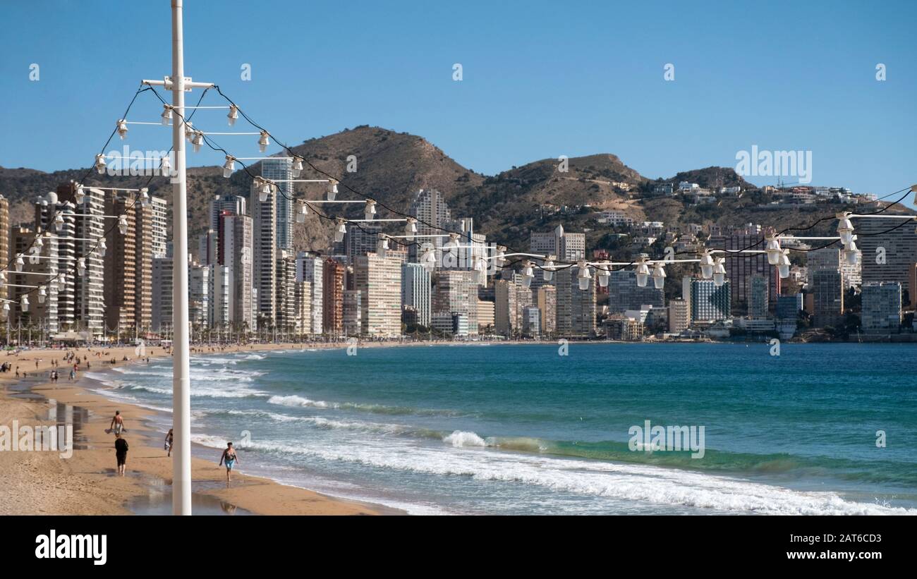 Les touristes marchant sur la plage Playa de Levante avec les gratte-ciel Rincón de Loix et le parc naturel Serra Gelada à l'arrière (Benidorm, Alicante, Espagne) Banque D'Images