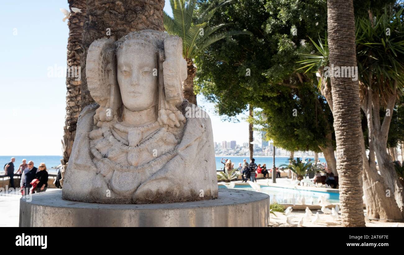 Dama de Elche réplique sculpture à côté de la plage Playa de Poniente avec des touristes marchant dans une journée ensoleillée (Benidorm, Costa Blanca, Alicante, Espagne) Banque D'Images