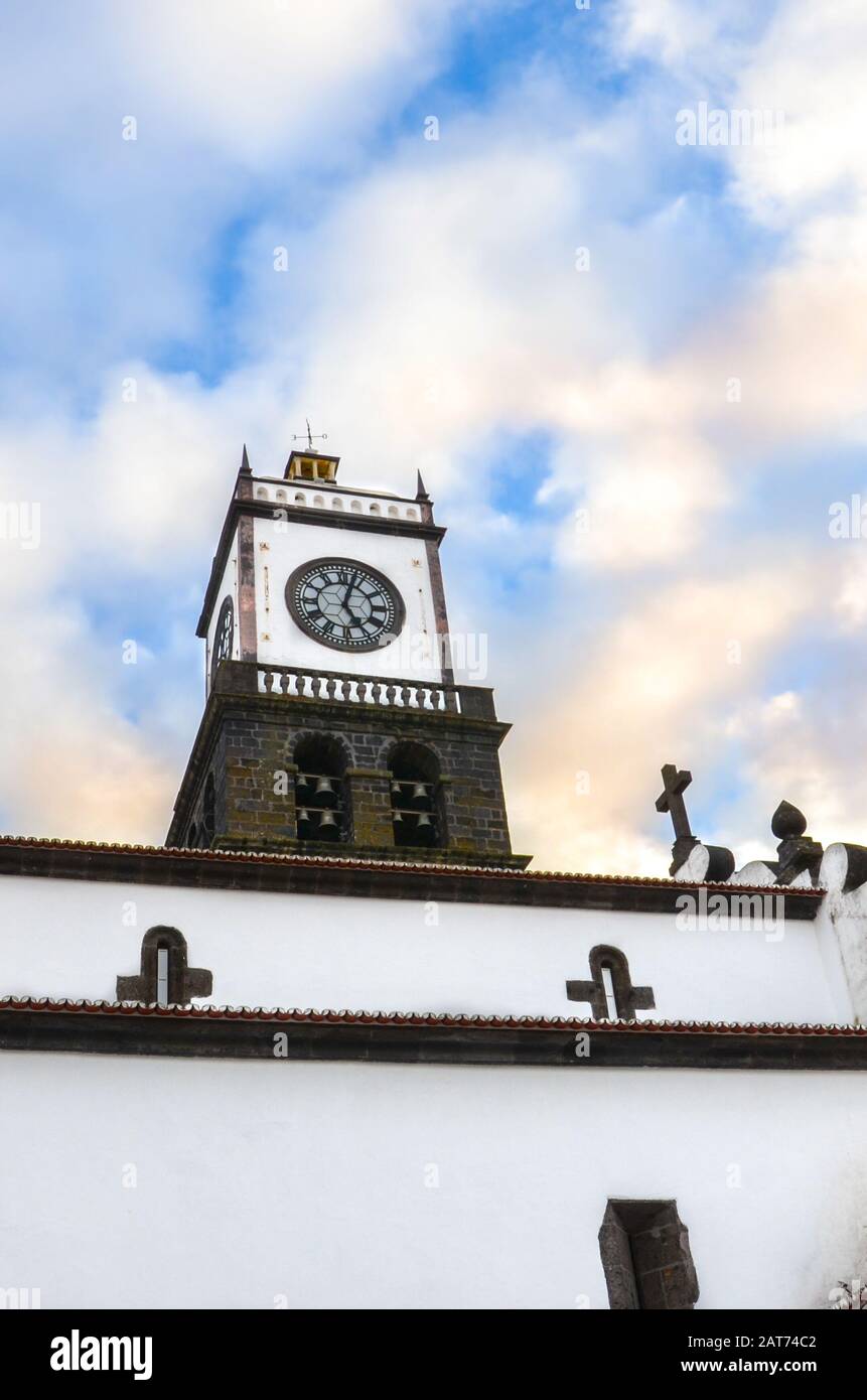 La façade extérieure de l'église Saint-Sébastien, Igreja Matriz de Sao Sebastiao, à Ponta Delgada, Açores, Portugal. Tour d'horloge blanche du dessous avec ciel bleu et nuages au-dessus. Coucher de soleil nuages. Banque D'Images