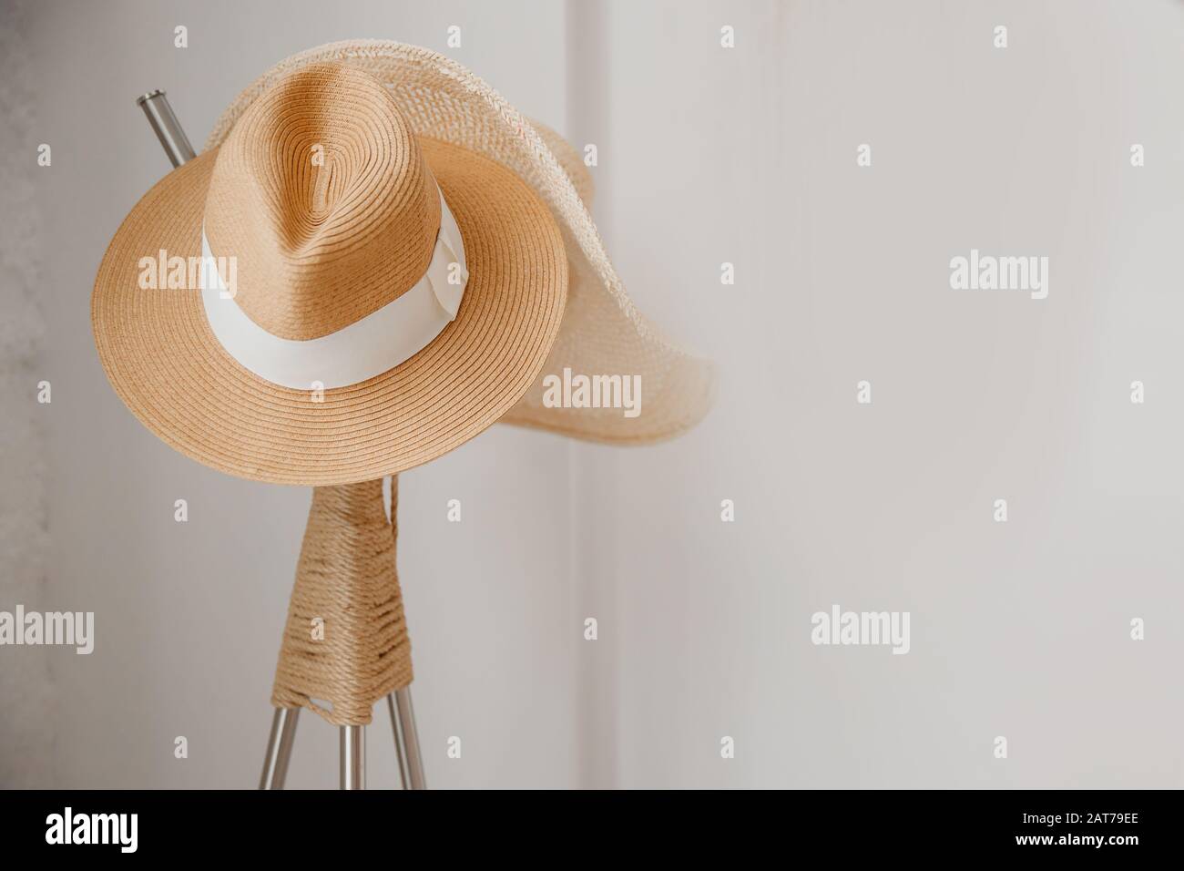 Chapeau de paille jaune accroché sur un cintre de manteau blanc en bois, minimaliste de style scandinave. Concept de voyage Banque D'Images