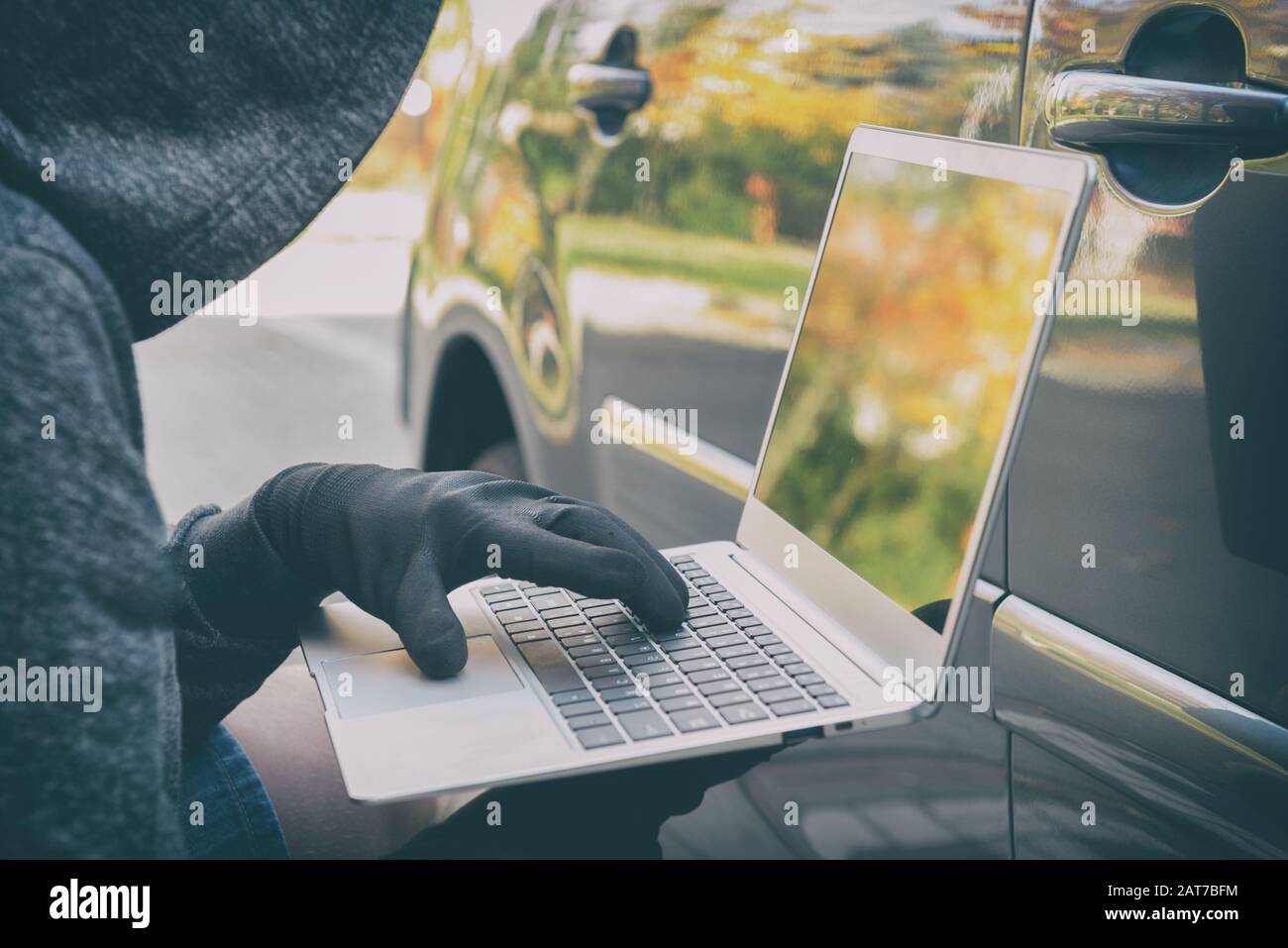 Le voleur tente de briser les systèmes de sécurité de la voiture avec ordinateur portable. Concept de voiture moderne Hacking Banque D'Images