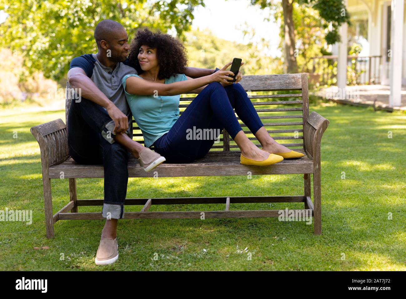Un jeune couple heureux assis sur un banc dans le jardin Banque D'Images
