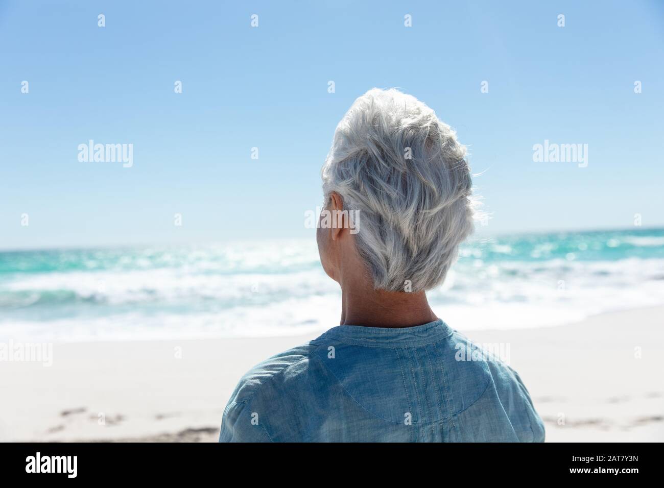 Vieille femme regardant la plage Banque D'Images