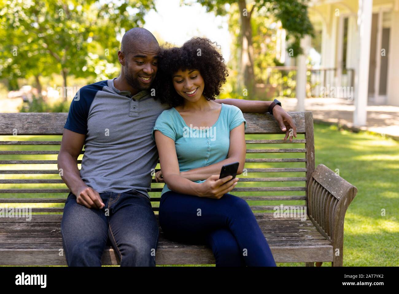 Un jeune couple heureux assis sur un banc dans le jardin Banque D'Images