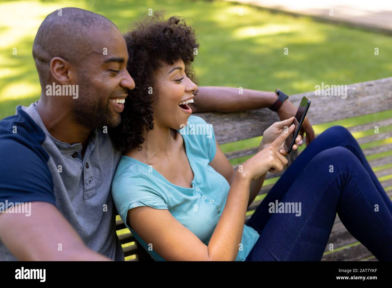 Un jeune couple heureux assis sur un banc dans le jardin Banque D'Images