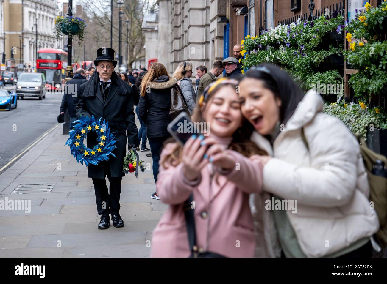 Londres, Royaume-Uni. 31 Janvier 2020. Deux jeunes filles prennent un selfie d'un homme vêtu d'une entreprise qui marche lentement le long de Whitehall avec le récif funéraire de l'UE. Banque D'Images