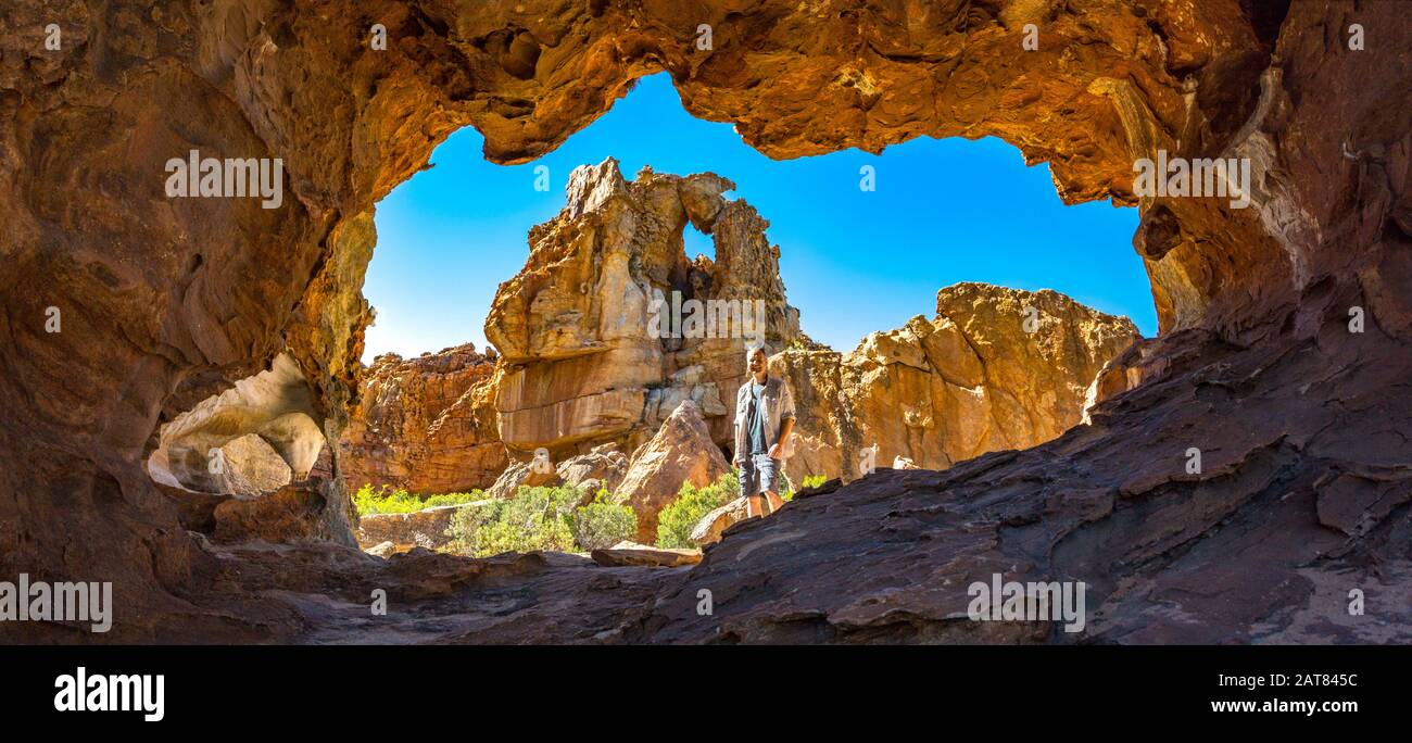 Homme en face d'une grotte avec une formation bizarre de roches en arrière-plan, Stadsaal, Cederberg Wilderness Area, Afrique du Sud Banque D'Images