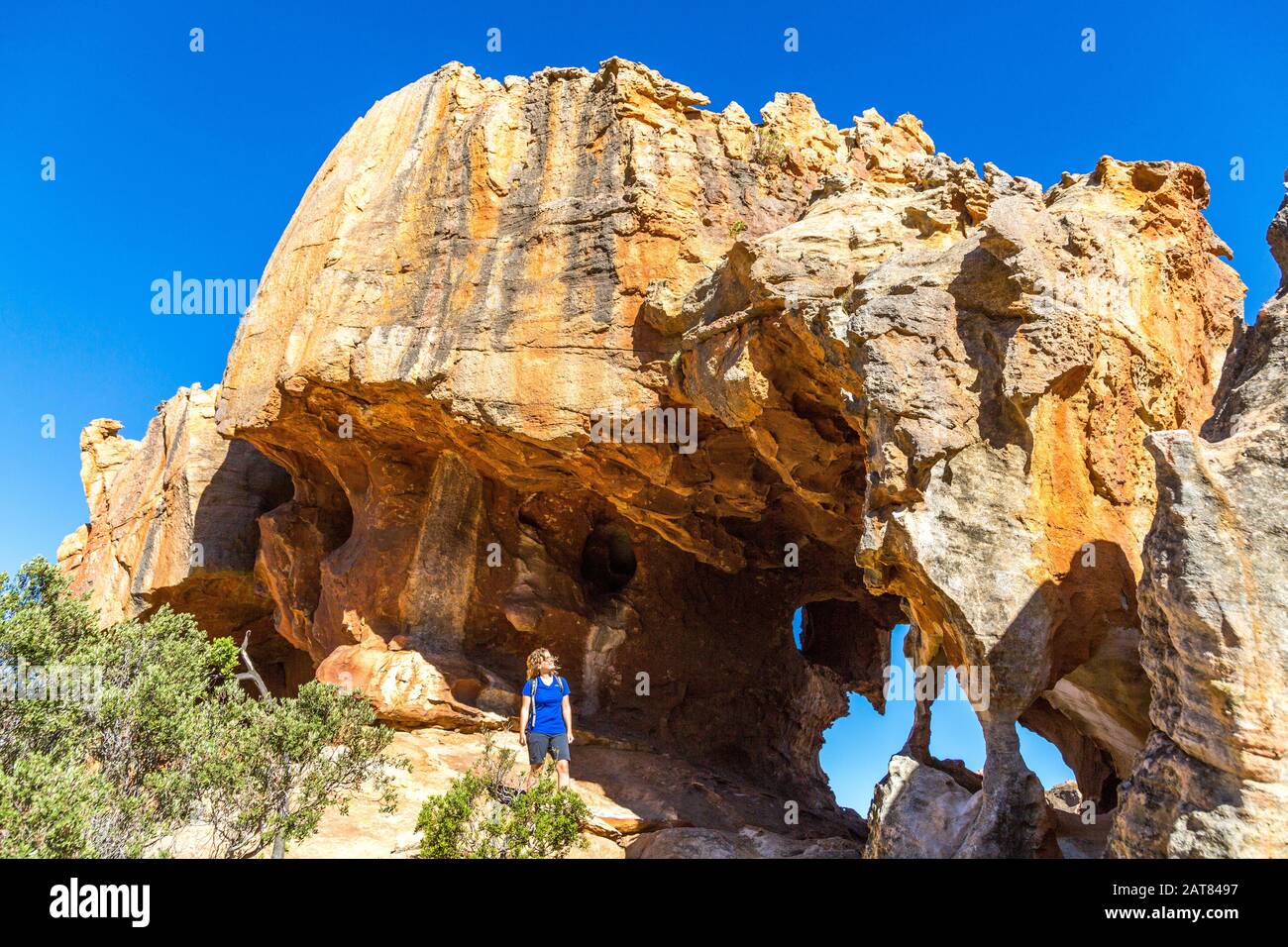 Jeune femme regardant une spectaculaire formation de roches avec arche et grotte, Stadsaal, Cederberg Wilderness Area, Afrique du Sud Banque D'Images