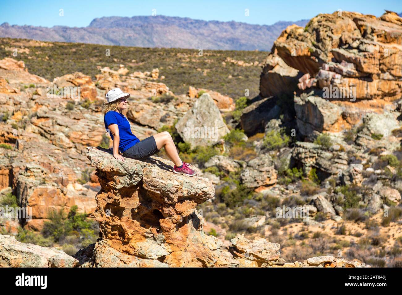 Jeune femme assise sur un rocher exposé et profitant de la vue sur un paysage bizarre, Stadsaal, Cederberg Wilderness Area, Afrique du Sud Banque D'Images