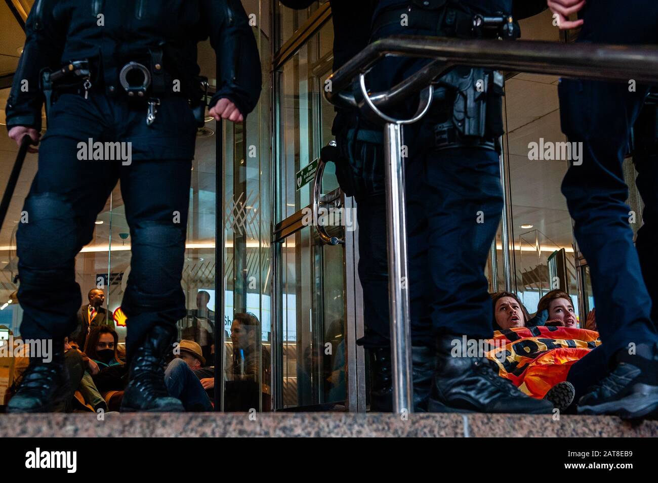 Un groupe d'activistes XR collés aux portes du cristal pendant la campagne. Une vingtaine d'activistes du groupe Rébellion de l'extinction ont montré au siège de Shell dans le cadre de la campagne Shell doit tomber, qui se déroule toute la semaine dans tout le pays. Certains militants de l'extinction se sont collés aux fenêtres et aux portes en cristal du bâtiment. Après avoir refusé de quitter le lieu, la plupart d'entre eux ont été arrêtés par la police. Banque D'Images