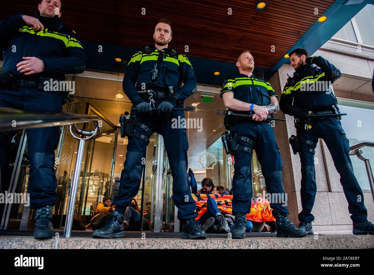 Police à la garde à côté d'un groupe d'activistes XR collés aux portes du cristal pendant la campagne. Une vingtaine d'activistes du groupe extinction Rebellion ont montré au siège de Shell dans le cadre de la campagne Shell doit tomber, qui se déroule toute la semaine dans tout le pays. Certains militants de l'extinction se sont collés aux fenêtres et aux portes en cristal du bâtiment. Après avoir refusé de quitter le lieu, la plupart d'entre eux ont été arrêtés par la police. Banque D'Images