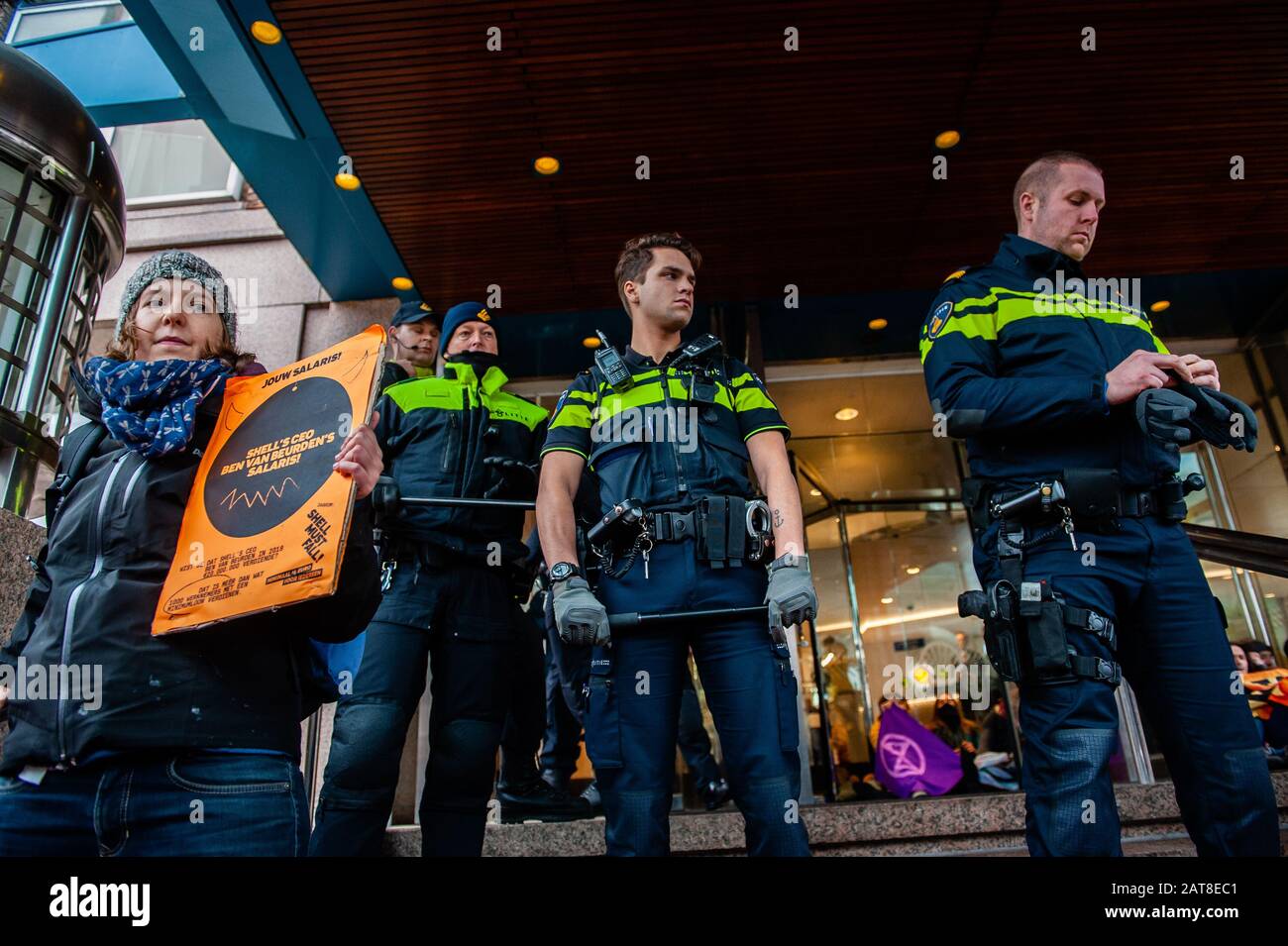Un militant du XR collé aux escaliers à côté de la police pendant la campagne. Une vingtaine d'activistes du groupe Rébellion de l'extinction ont montré au siège de Shell dans le cadre de la campagne que Shell doit tomber, qui se déroule toute la semaine dans tout le pays. Certains militants de l'extinction se sont collés aux fenêtres et aux portes en cristal du bâtiment. Après avoir refusé de quitter le lieu, la plupart d'entre eux ont été arrêtés par la police. Banque D'Images