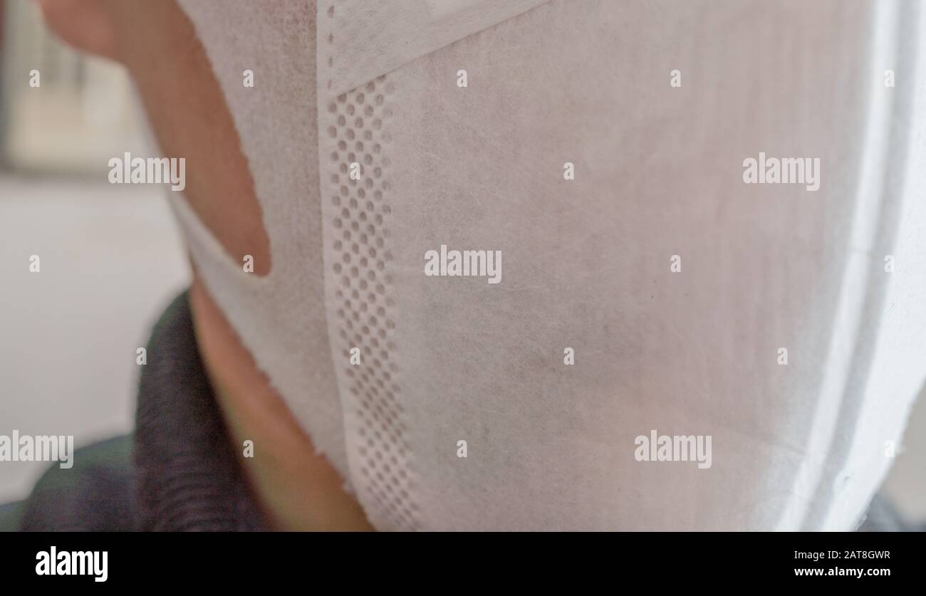 Gros plan sur le visage d'un jeune homme portant un masque médical ou chirurgical Banque D'Images