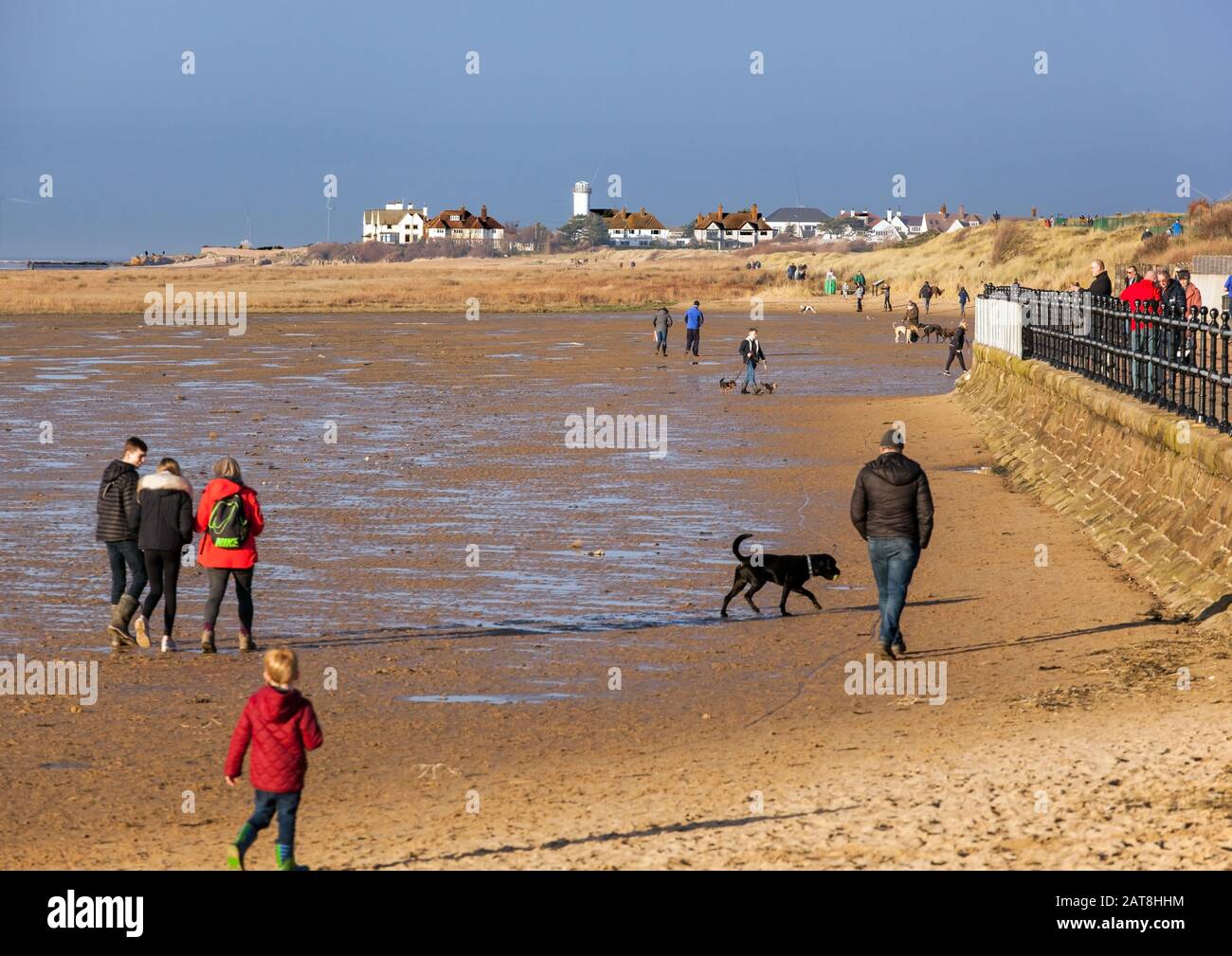 Les gens qui marchaient sur la plage de West Kirby vers Hoylake, sur la péninsule de Wirral, en Angleterre, pendant une journée d'hiver ensoleillée Banque D'Images