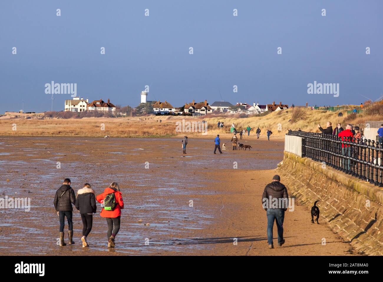 Les gens qui marchaient sur la plage de West Kirby vers Hoylake, sur la péninsule de Wirral, en Angleterre, pendant une journée d'hiver ensoleillée Banque D'Images