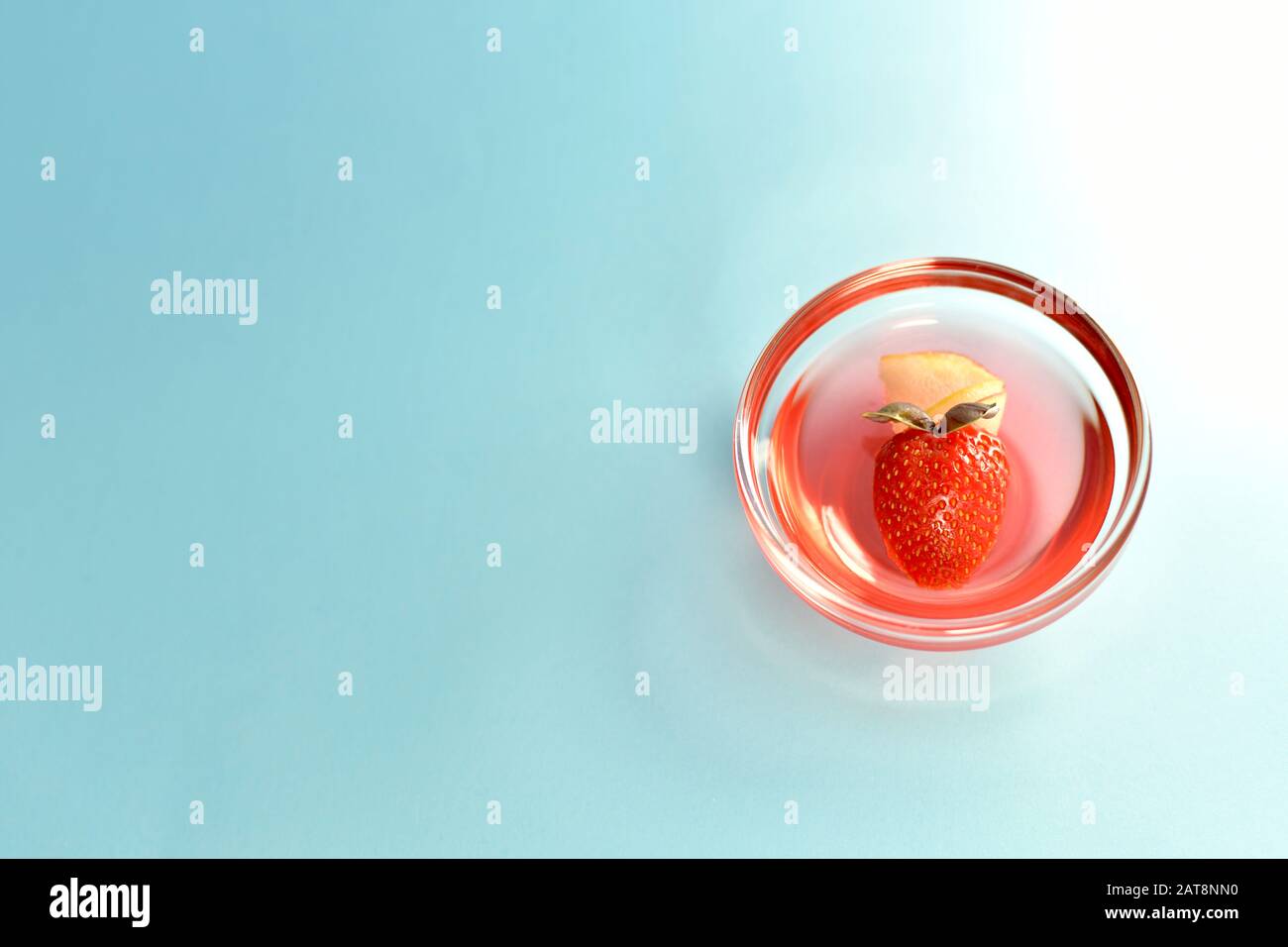 Gelée avec fraise en forme de coeur sur un fond bleu illuminé par un faisceau de lumière sur la droite. Banque D'Images