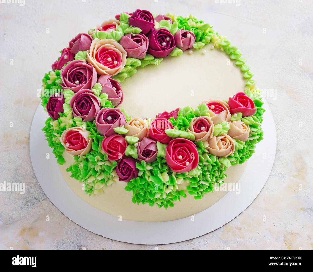 Gâteau blanc festif lumineux avec fleurs lumineuses faites de la crème, un gâteau de mariage, pour une femme. Banque D'Images