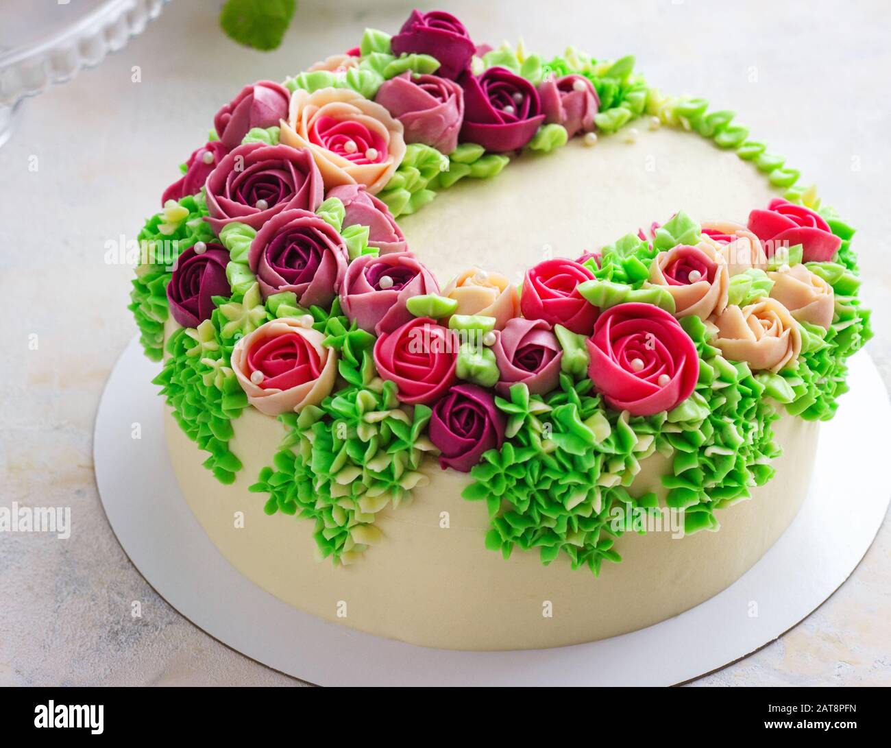 Gâteau blanc festif lumineux avec fleurs lumineuses faites de la crème, un gâteau de mariage, pour une femme. Banque D'Images