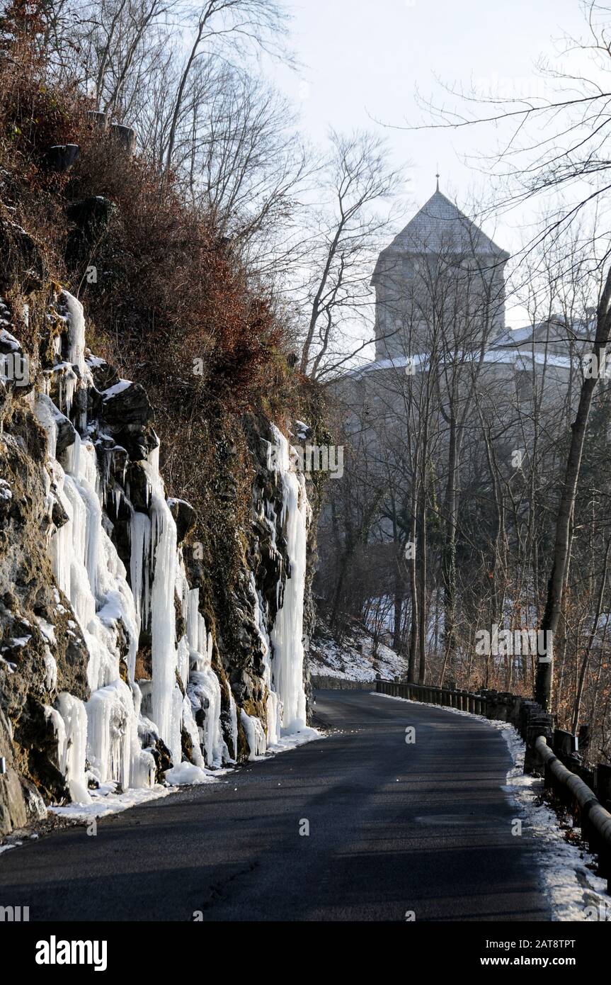 Les chutes d'eau gelées à côté d'une route à Vaduz au Liechtenstein. Au loin se trouve le château royal, la résidence de la famille royale . Banque D'Images