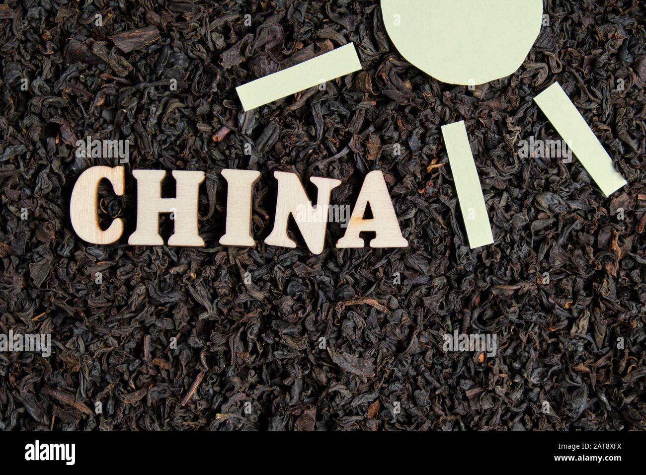 Inscription en bois de la Chine avec symbole du soleil sur fond de thé noir dispersé. Concept de vente de thé chinois. Banque D'Images