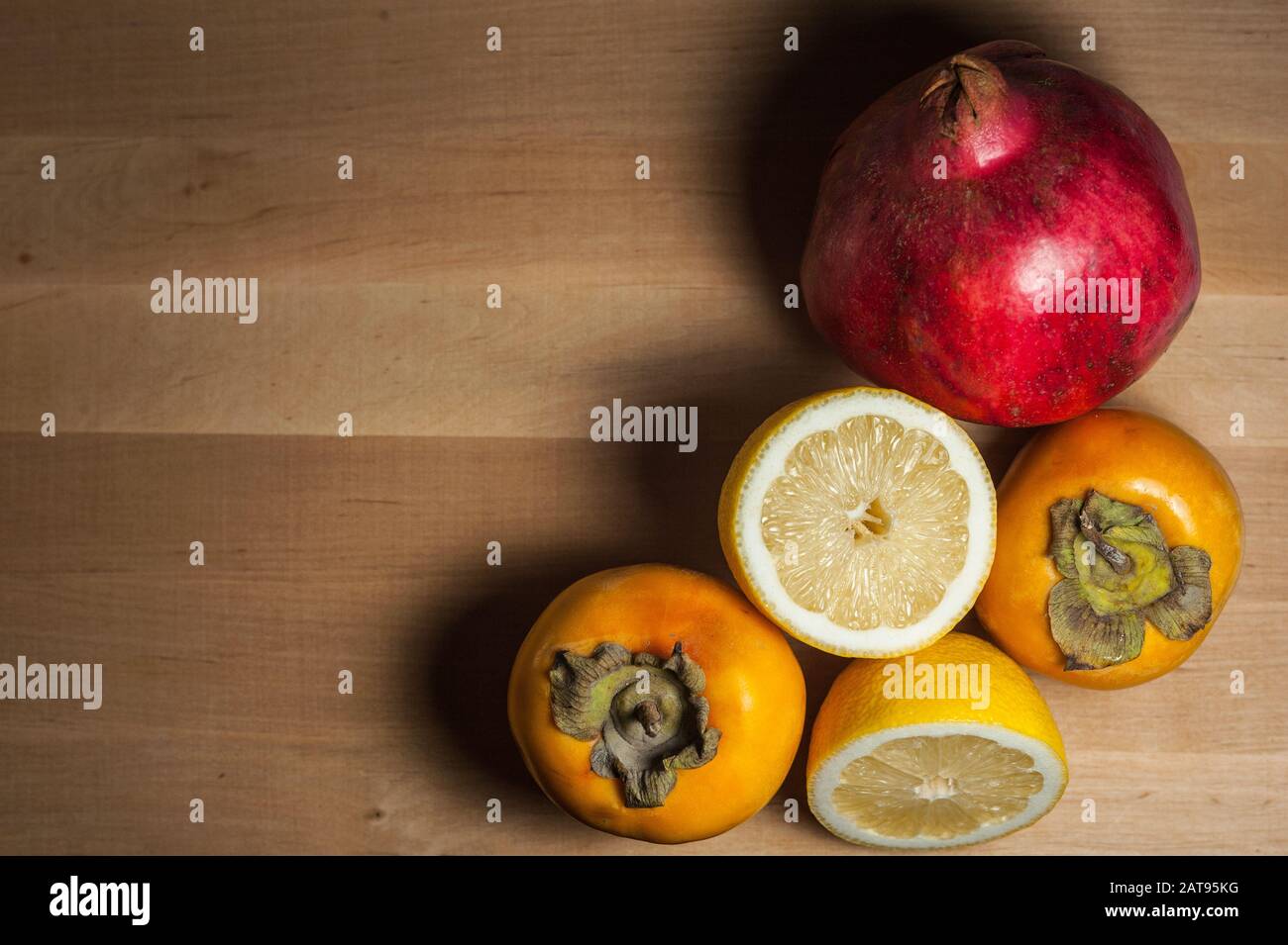 grenade mûre, citron et persimmon sur une planche en bois Banque D'Images