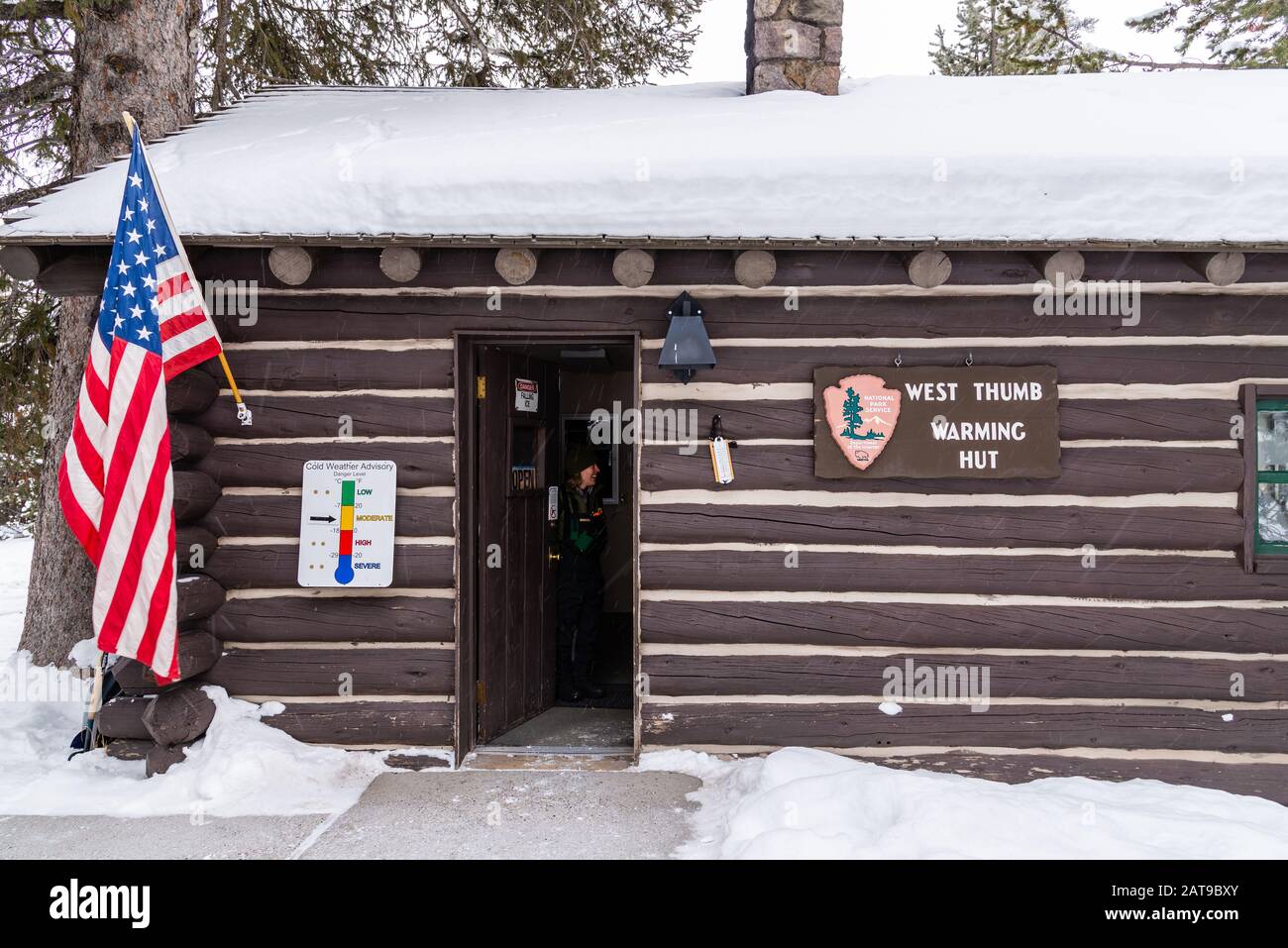 Parker ranger ouvre la porte pour accueillir les visiteurs de la cabane De Réchauffement de la main Ouest en hiver. Yellowstone National Park, Wyoming, États-Unis Banque D'Images