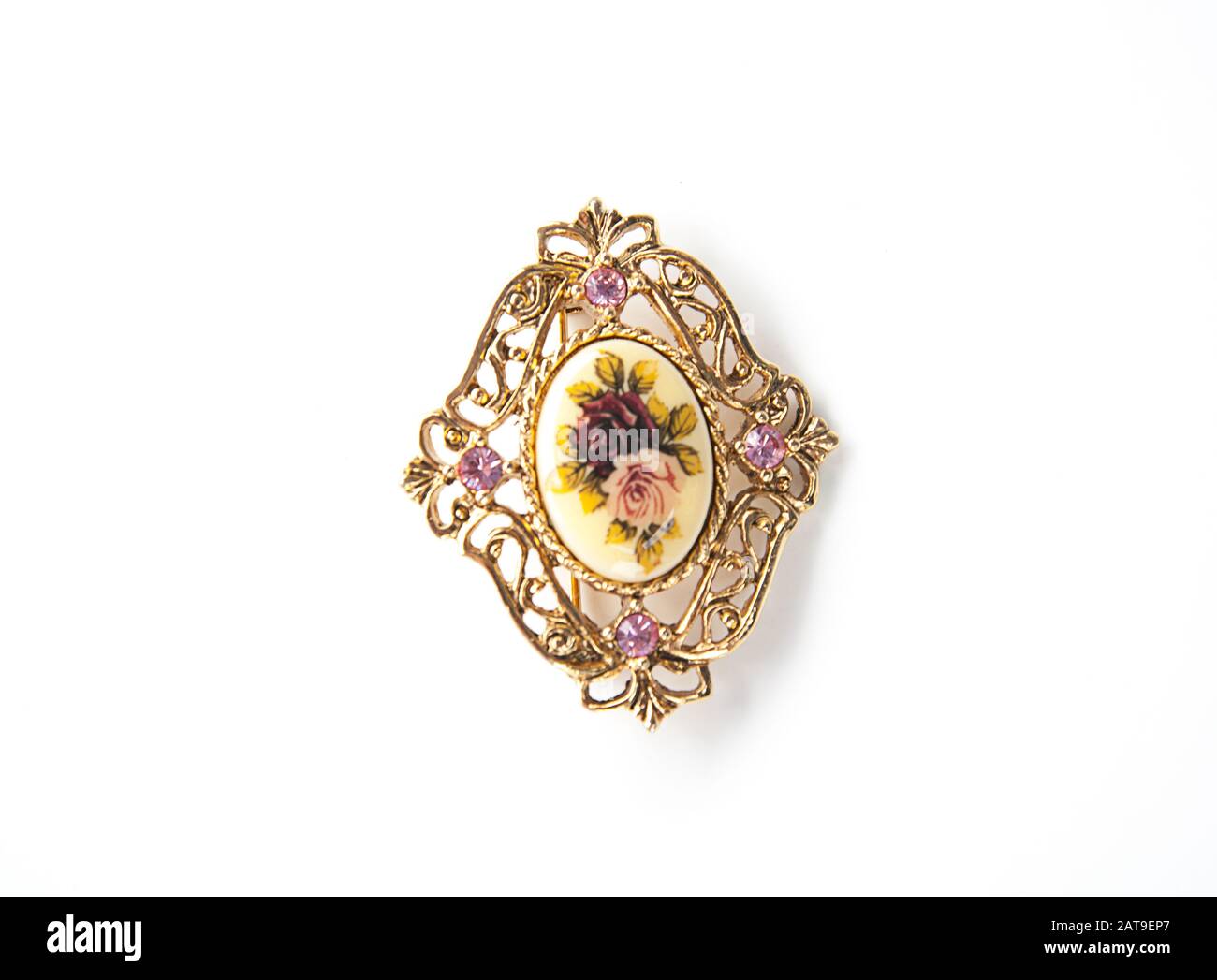 Bijoux à broche en or et fleurs roses isolés sur un fond clair. Pierres gemmes améthystes violettes sur cet accessoire de mode vintage. Banque D'Images